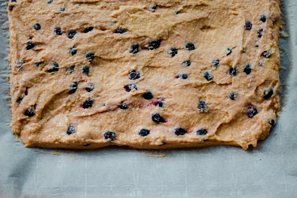 Blueberry bars dough spread on a baking sheet lined with parchment paper