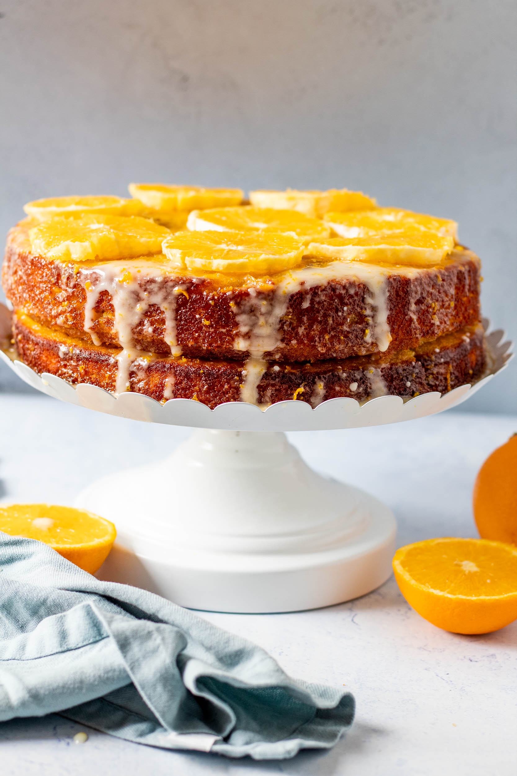 Almond Orange cake on a stand with cut oranges around