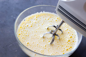 Eggs and sugar in a bowl, while they are blended with a hand mixer