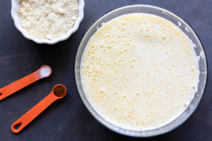 A bowl with eggs and sugar mixture, a small bowl of almond flour, and 1/2 tsp of baking soda and 1 tsp of cinnamon