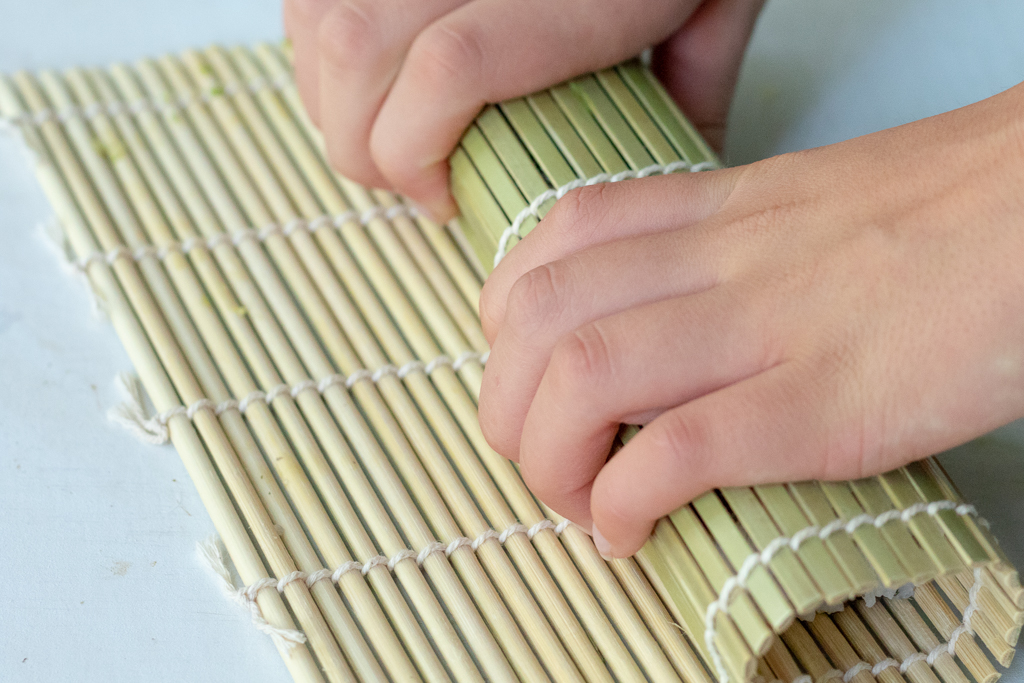 Rolling a sushi roll with a bamboo mat