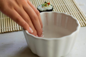 Hand getting slightly wet in a bowl of water