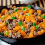 Cooked sweet potatoes and ground beef in an iron skillet