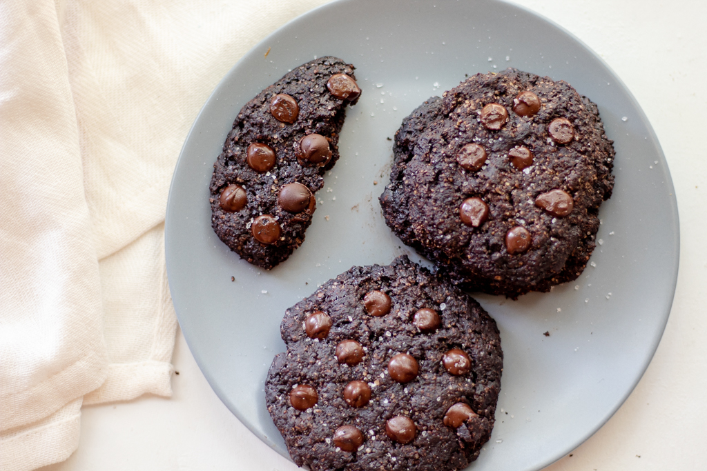 Three Vegan Chocolate Cookies on a plate, with one half cookie and 2 full cookies