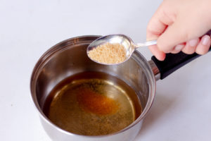 Someone adding sugar to a saucer pan with water 
