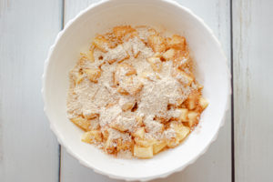 A white bowl with apples covered with sugar and oat flour