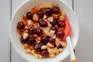 A white bowl with apples and frozen cherries
