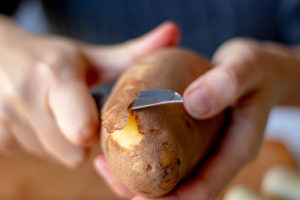 someone peeling a white potato
