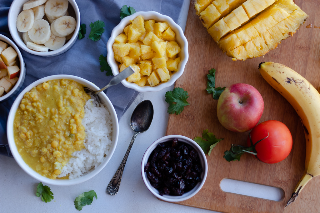 A bowl of curry over rice and a spread of curry ingredients