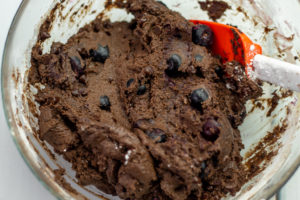 cupcake batter with chocolate chips and blueberries mixed in