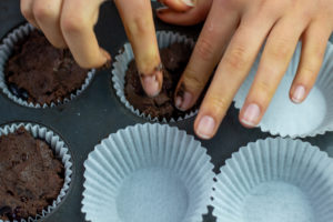 someone adding cupcake batter to the muffin pan