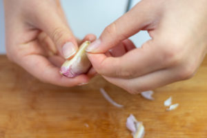 someone peeling a garlic clove