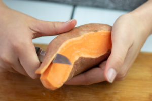 someone peeling a sweet potato