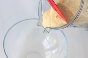 Someone adding chickpea dough to a bowl