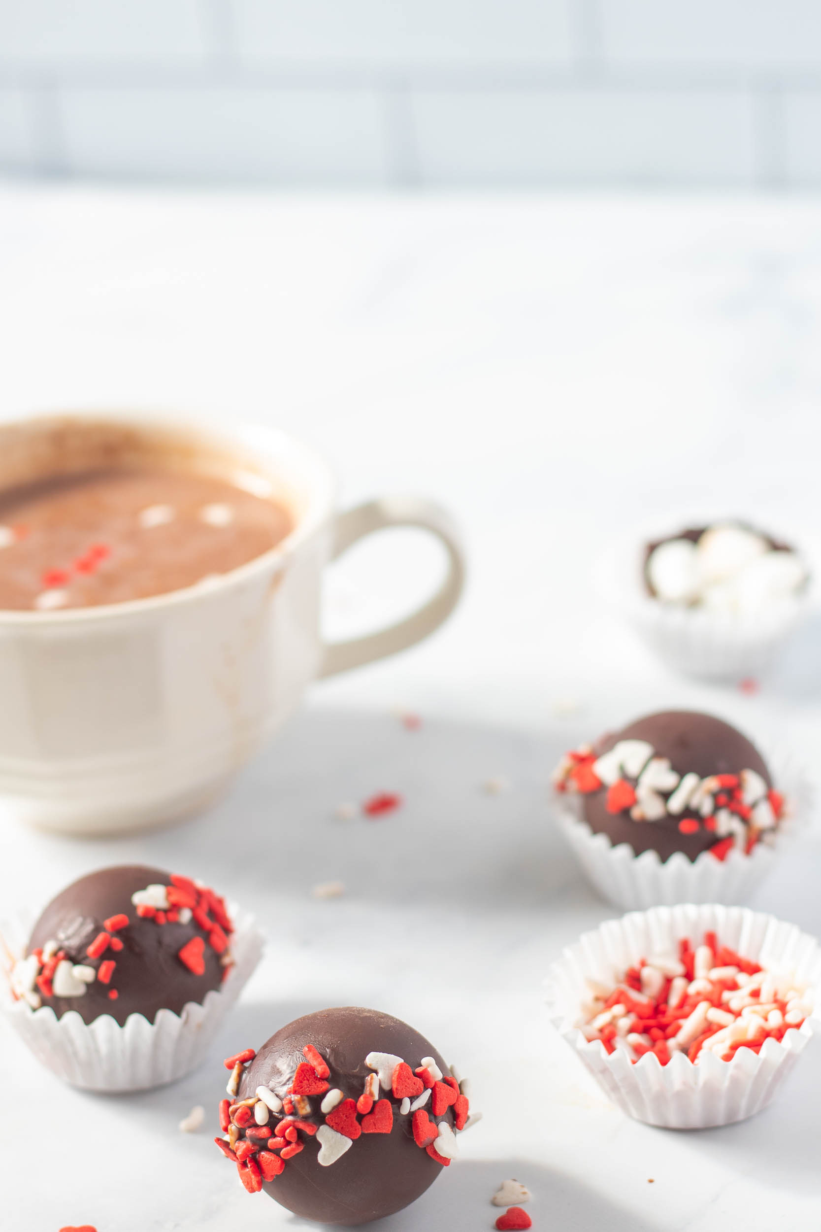 valentine's day hot chocolate bombs next to a cup of hot cocoa