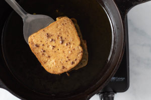 piece of soaked bread cooking in an iron skillet
