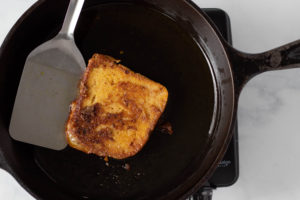 piece of french bread cooking in the skillet