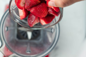 Adding strawberries to a blender