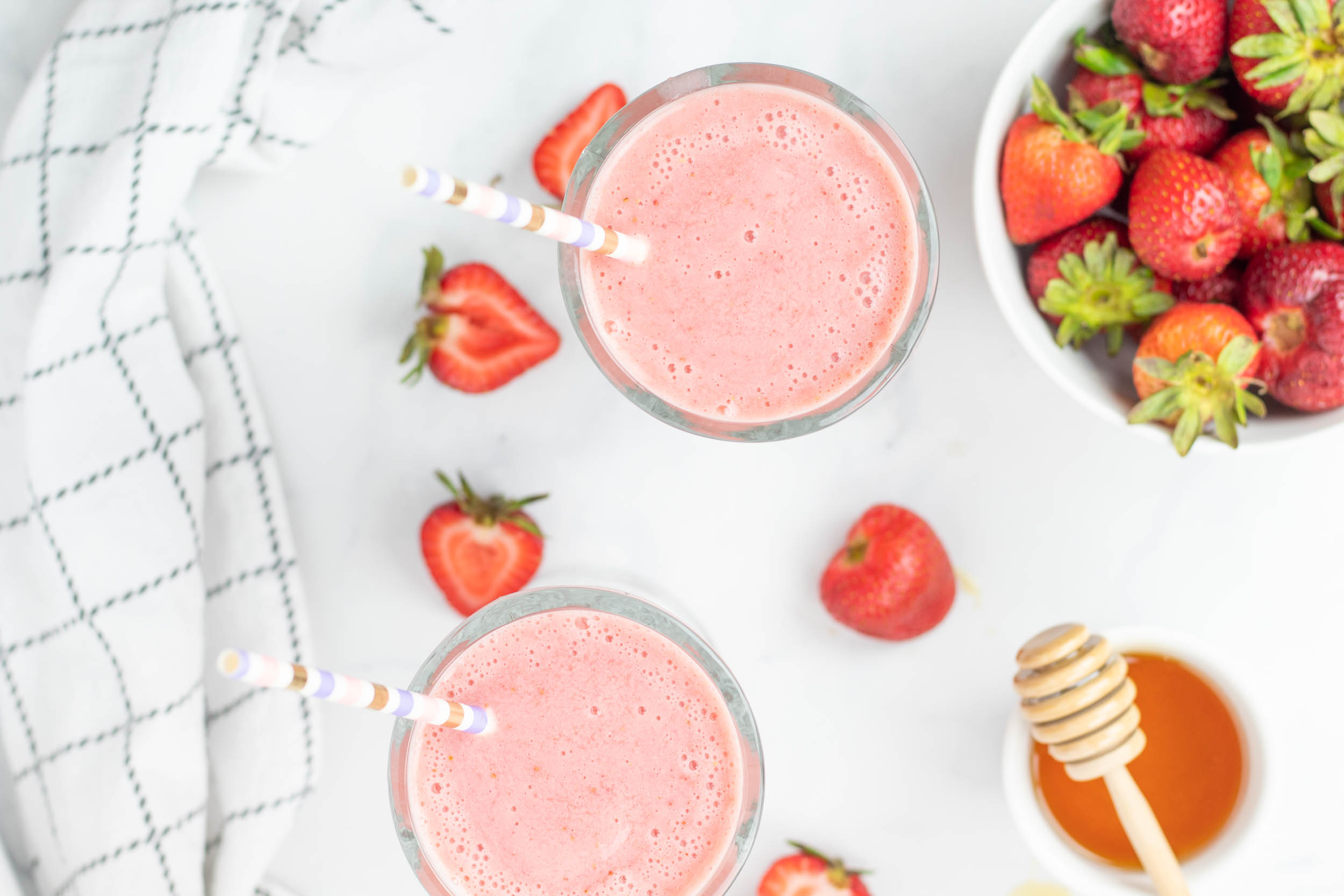 Strawberry smoothie in two glasses with straws