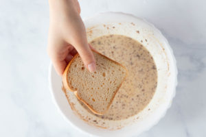 someone adding a piece of bread to the batter