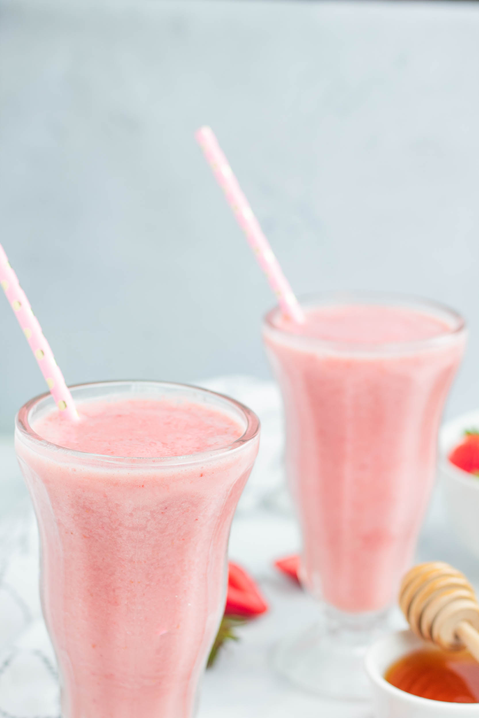 Strawberry smoothie in two glasses with straws